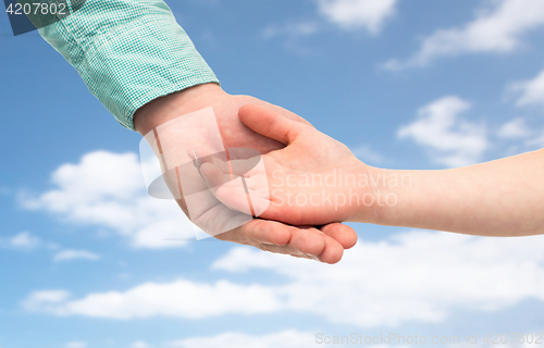 Image of father and child holding hands over blue sky