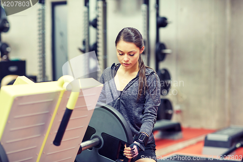 Image of young woman adjusting leg press machine in gym