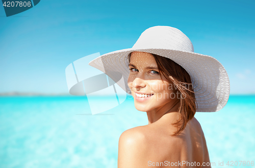 Image of smiling young woman in sun hat on summer beach