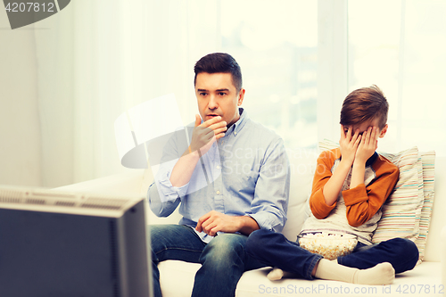 Image of father and son watching horror movie on tv at home