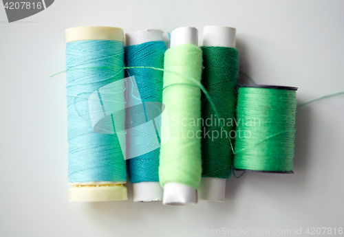 Image of green and blue thread spools on table