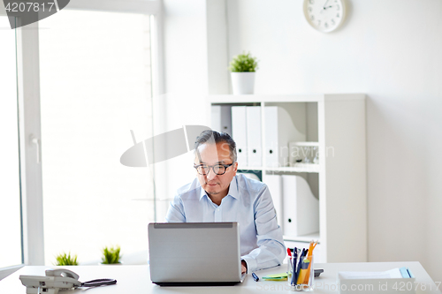 Image of businessman in eyeglasses with laptop office
