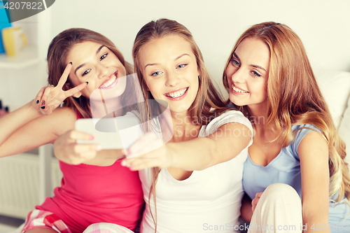 Image of teen girls with smartphone taking selfie at home