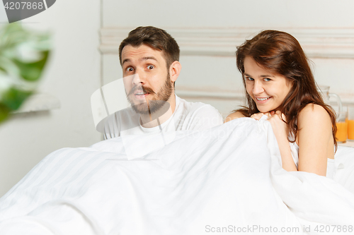 Image of Young adult heterosexual couple lying on bed in bedroom