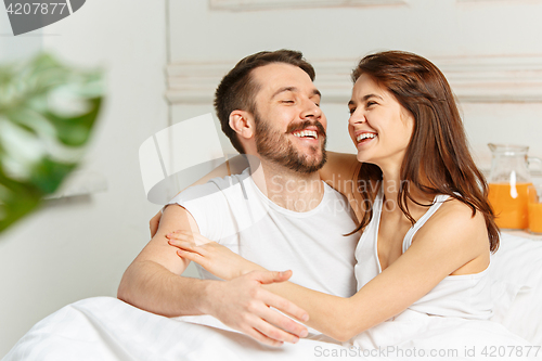 Image of Young adult heterosexual couple lying on bed in bedroom