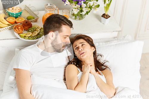 Image of Young adult heterosexual couple lying on bed in bedroom