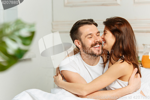 Image of Young adult heterosexual couple lying on bed in bedroom