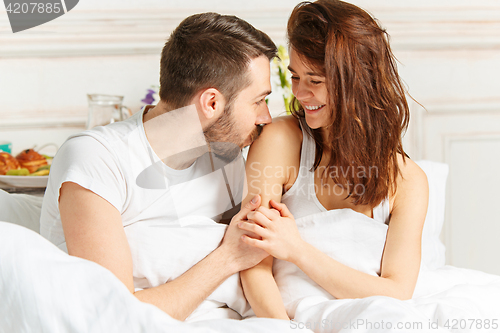 Image of Young adult heterosexual couple lying on bed in bedroom