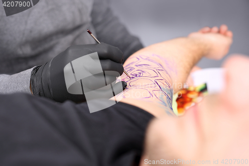 Image of Tatoo drawing on his shoulder. Tattoo, tattoo artist does the tattoo on the man&#39;s hand.