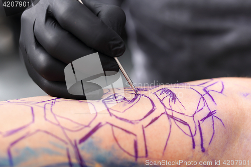 Image of Tatoo drawing on his shoulder. Tattoo, tattoo artist does the tattoo on the man&#39;s hand.