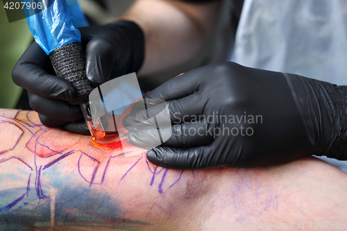 Image of Tattooer tattooing color tattoo on his hand man