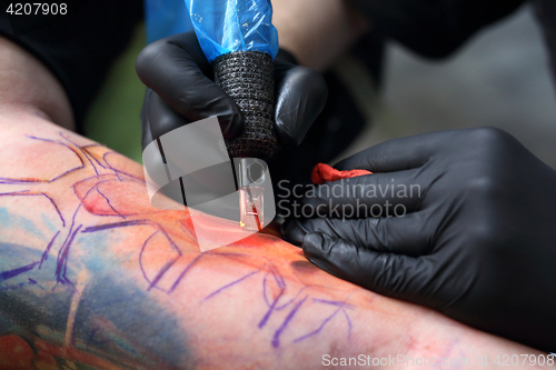 Image of The tattoo parlor. A tattoo artist tattooing color tattoo on his hand man Tattooer tattooing color tattoo on his hand man