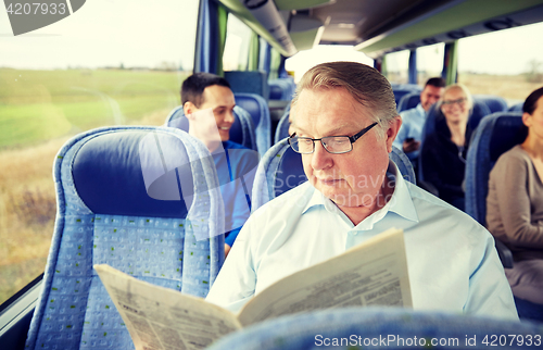 Image of happy senior man reading newspaper in travel bus