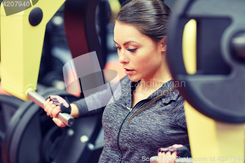 Image of woman flexing muscles on chest press gym machine 