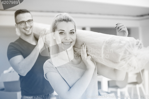 Image of couple carrying a carpet moving in to new home