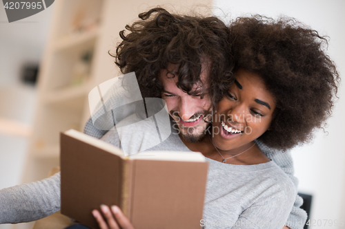 Image of multiethnic couple hugging in front of fireplace