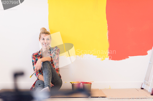 Image of young female painter sitting on floor