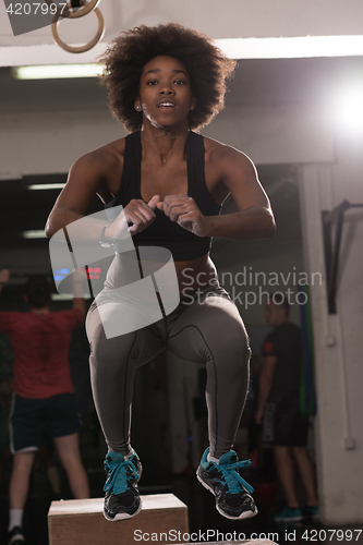 Image of black female athlete is performing box jumps at gym