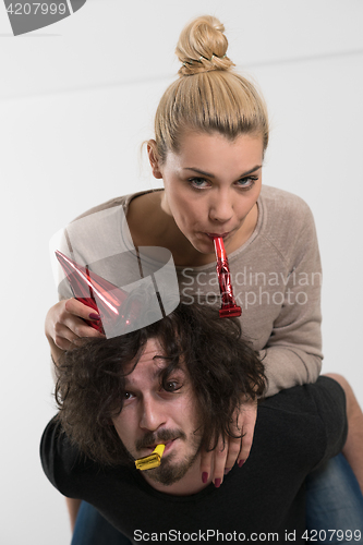 Image of couple in party hats blowing in whistle