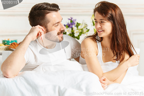 Image of Young adult heterosexual couple lying on bed in bedroom