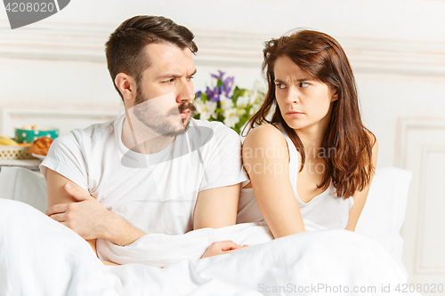 Image of Young adult heterosexual couple lying on bed in bedroom