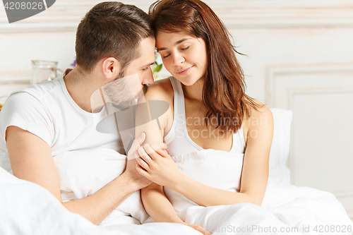 Image of Young adult heterosexual couple lying on bed in bedroom