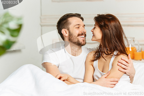 Image of Young adult heterosexual couple lying on bed in bedroom