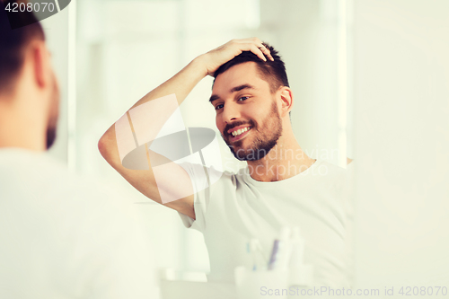 Image of happy young man looking to mirror at home bathroom