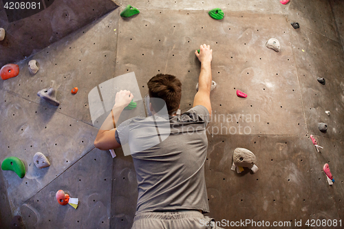 Image of young man exercising at indoor climbing gym wall