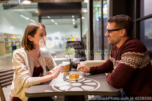 Image of happy couple eating cake for dessert at cafe