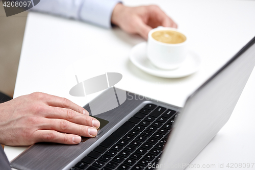 Image of close up of male hands with laptop and coffee cup