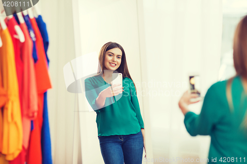 Image of woman with smartphone taking mirror selfie at home