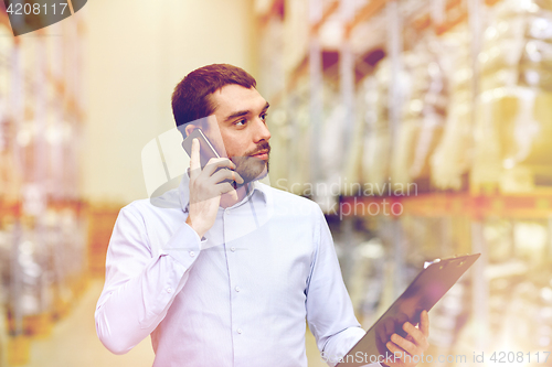 Image of man with clipboard and smartphone at warehouse