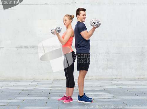 Image of sportive man and woman with dumbbells