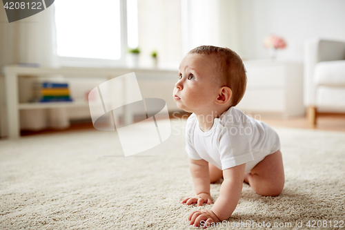 Image of little baby in diaper crawling on floor at home