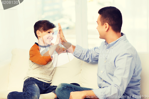 Image of happy father and son doing high five at home