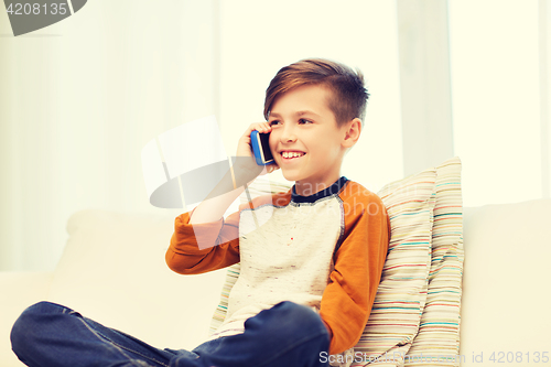 Image of happy boy calling on smartphone at home