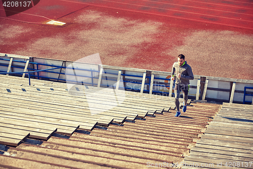 Image of happy young man running upstairs on stadium