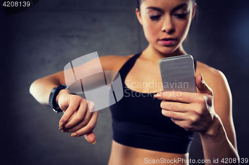 Image of woman with heart-rate watch and smartphone in gym