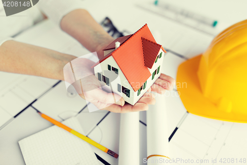 Image of close up of hands with house model above blueprint