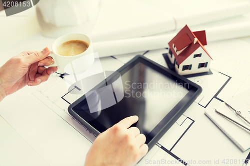 Image of close up of hand with blueprint and tablet pc