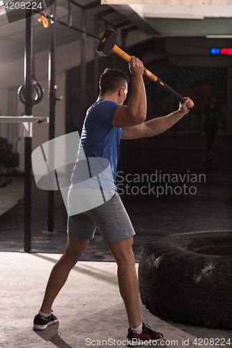 Image of man workout with hammer and tractor tire