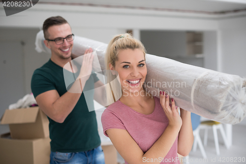 Image of couple carrying a carpet moving in to new home