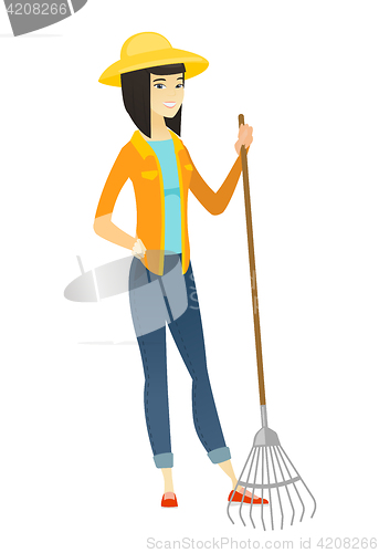 Image of Young asian farmer holding gardening rake.