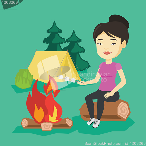 Image of Woman roasting marshmallow over campfire.