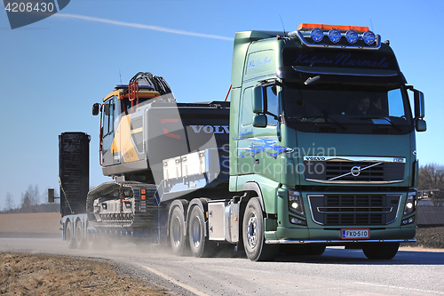 Image of Volvo FH16 Hauls Construction Equipment Along Highway