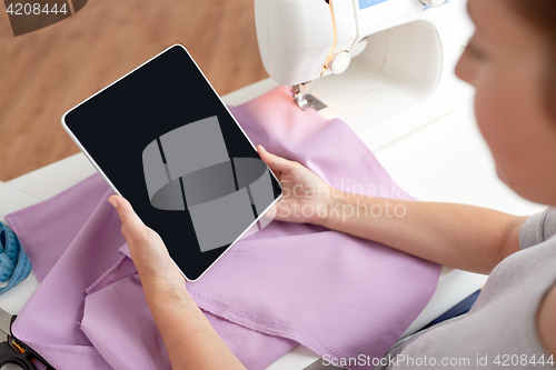 Image of tailor with sewing machine, tablet pc and fabric