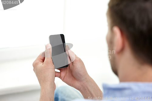 Image of close up of man holding black smartphone at home