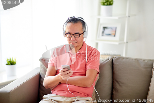 Image of man with smartphone and headphones at home