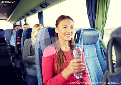 Image of happy young woman with water bottle in travel bus